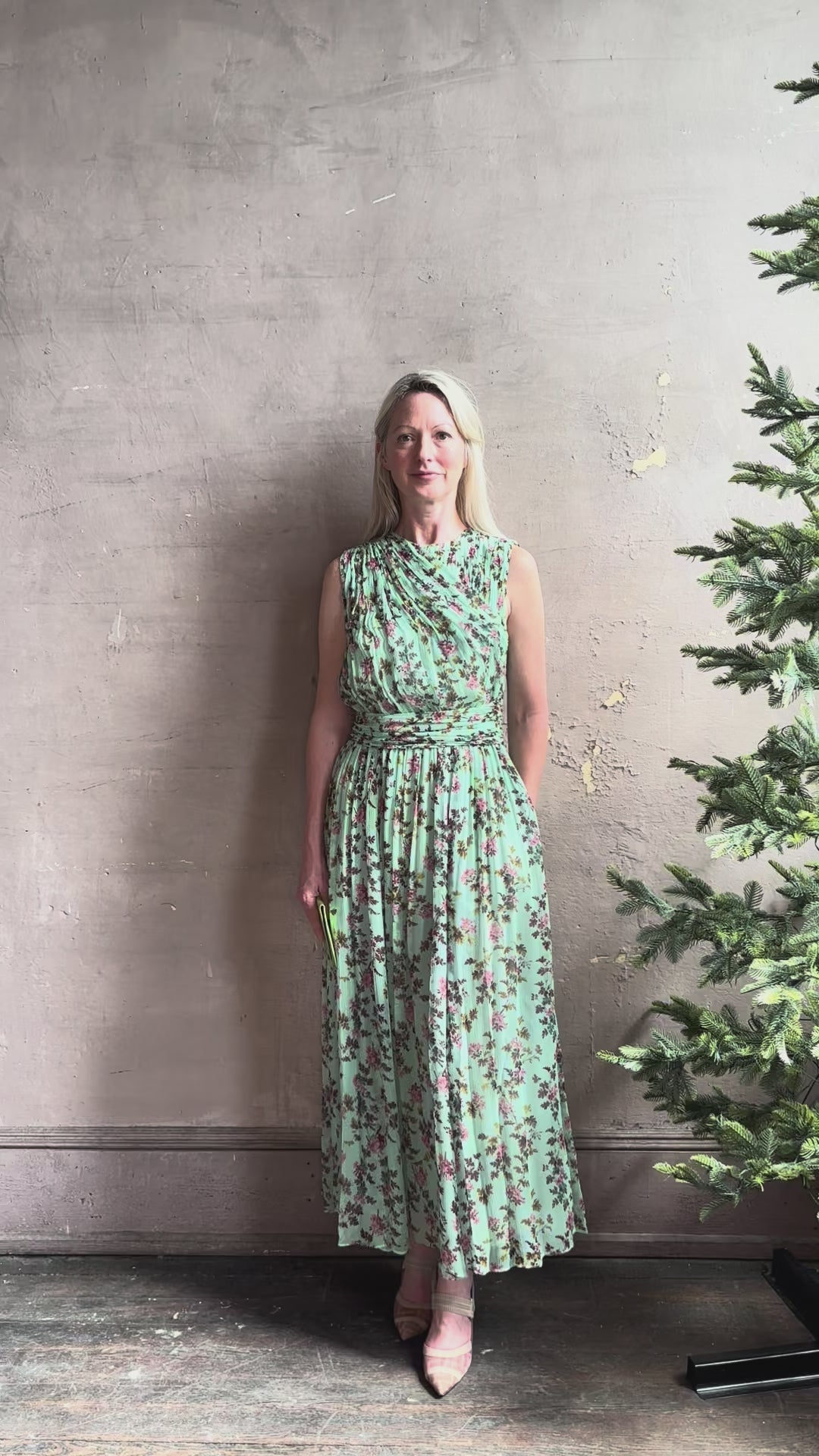 Mature woman reviewing  women's designer celestina silk maxi dress rendered in a mint green ground adorned with delicate brown and pink florals from Ulla Johnson that is sleevesless with gathered fabric bodice and waistband