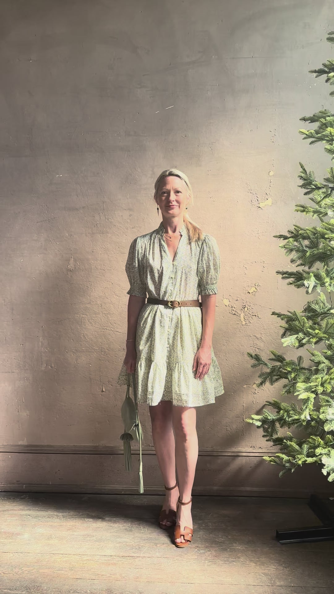 Mature woman reviewing the short Phoebe Dress from Trovata rendered in a charming coastal inspired floral print and crafted from cotton with button front, ruffle lined short sleeves and v-neck