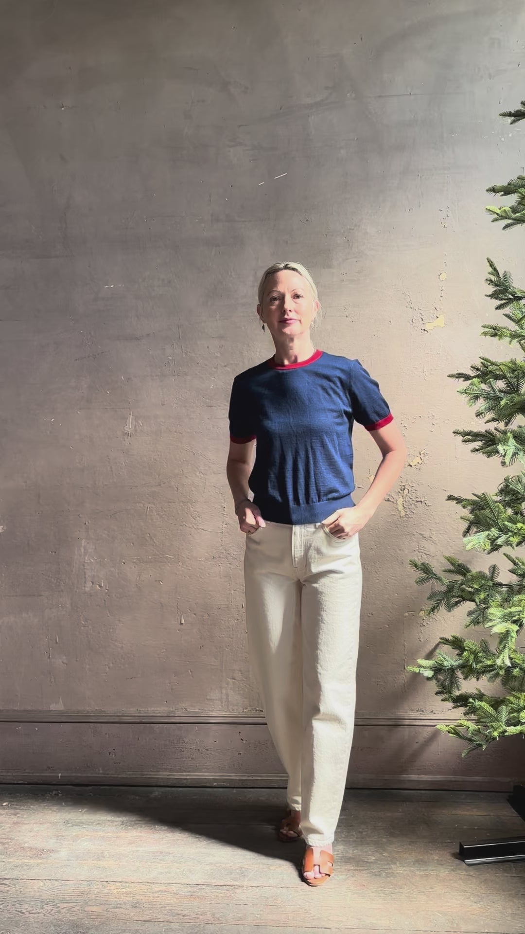 Mature woman reviewing women's designer cashmere Airy short sleeve Ringer Tee from Guest in Residence rendered in a navy body with carmine ringer detailing and crafted from 100% lightweight cashmere with a crew neckline
