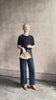 Mature woman reviewing designer Ulla Johnson Adria crossbody bag with raffia-textured exterior and removeable handle that can double as a clutch in a warm neutral tone