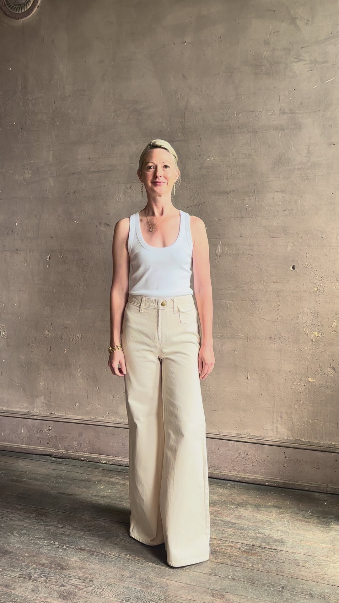 Mature woman reviewing women's luxury designer denim by Ulla Johnson Odelia Jean handcrafted from 100% cotton in Los Angeles California with a high-rise and elegant slimmer wide leg