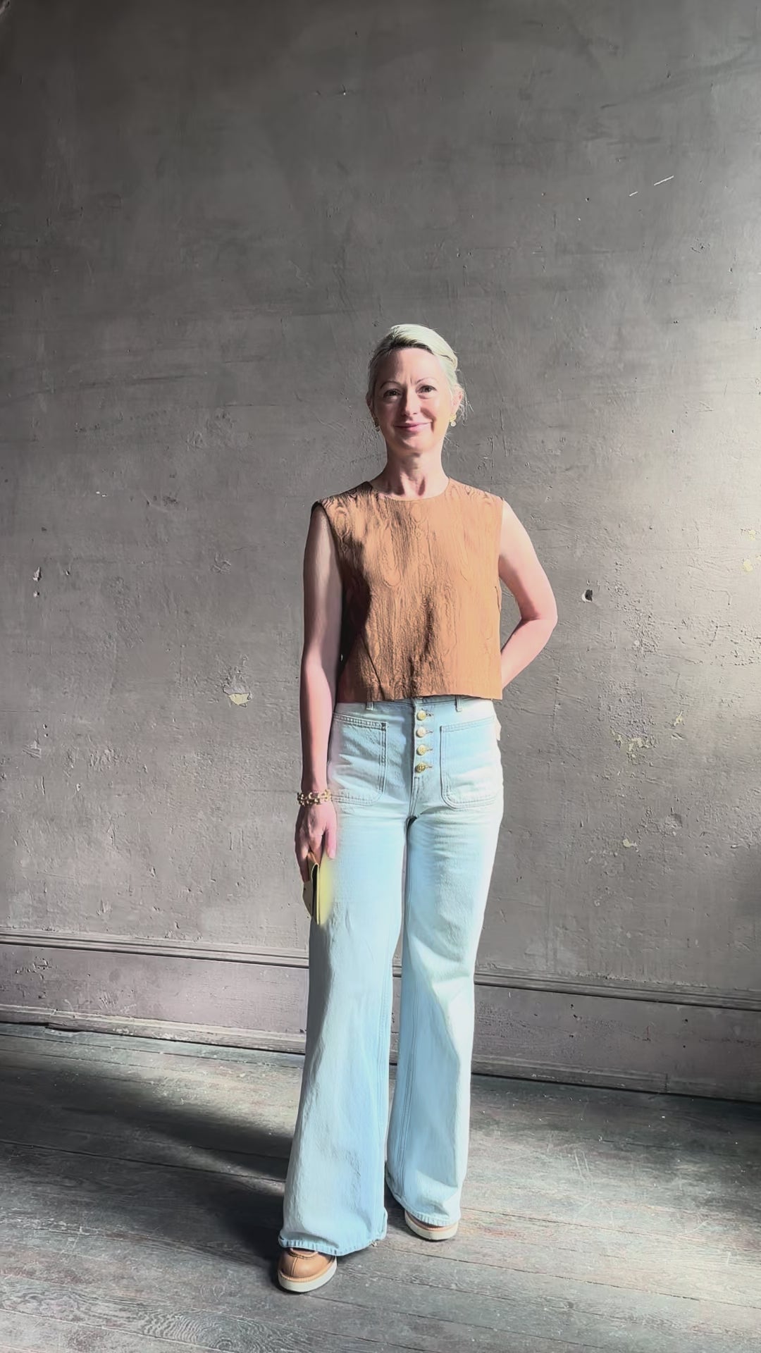 Mature woman reviewing a brown faux boise patterned sleeveless viscose top by designer Rachel Comey with a crew neckline and button back closure