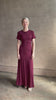 Mature woman reviewing the Noelle designer dress from Proenza Schouler in a deep wine hue with elevated back draping detail short sleeves and crew neck
