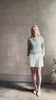 Mature woman reviewing elevated tailored Cisco Shorts from TWP rendered in a soft bone white and crafted in the USA using a viscose and  linen blend fabric with side seam pockets, belt loops, single front pleat and cuffed at the bottom