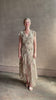 Mature woman reviewing the Cap Sleeve Anenel maxi Dress from luxury designer Veronica Beard rendered in a soft khaki, green, and pink paisley print and crafted in silk with cap sleeves, v- neckline, and asymmetrical hem all finished with soft feminine ruffles in a timeless A-line silhouette
