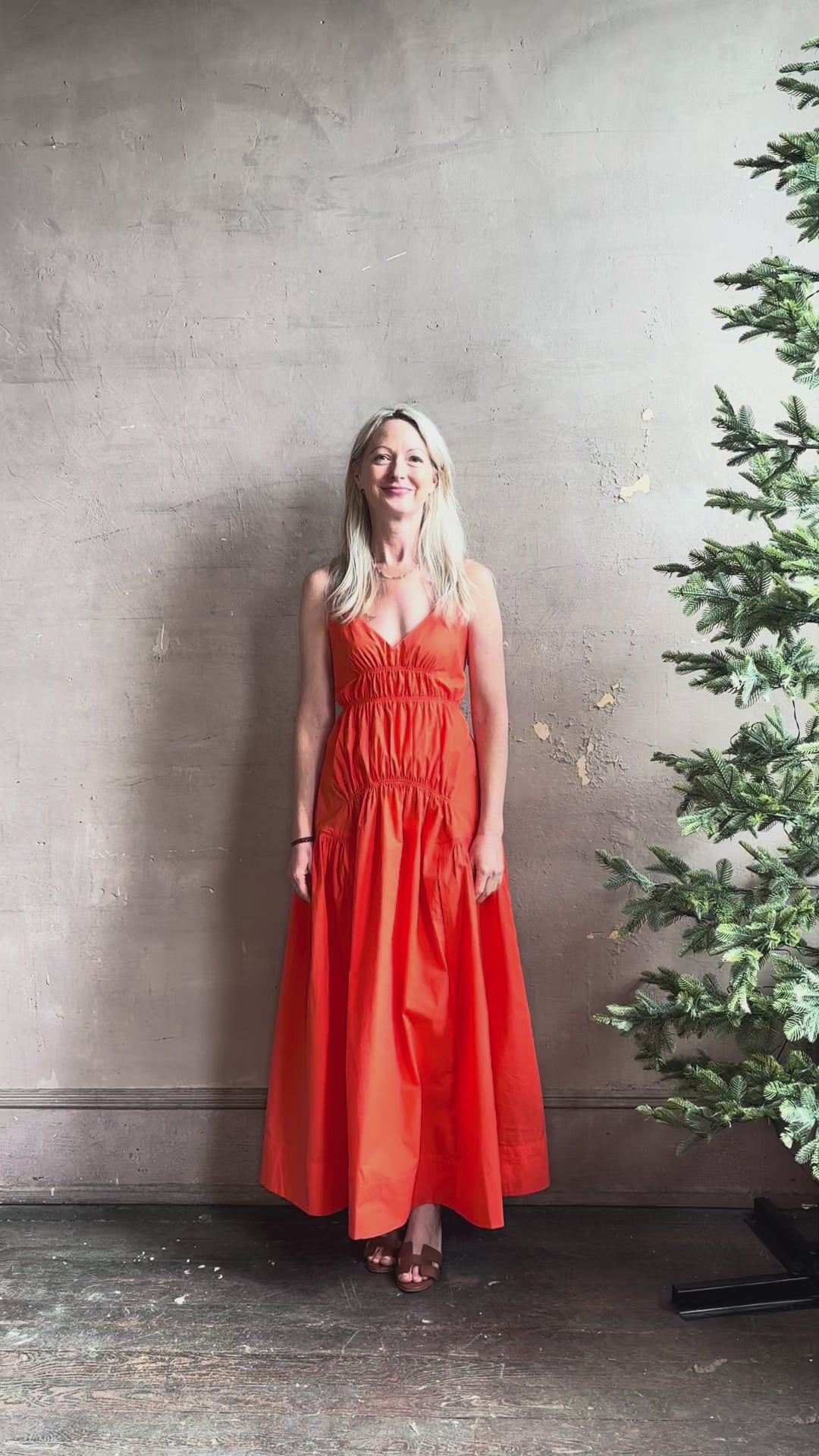 Mature woman reviewing  Michelyn maxi designer Dress from Proenza Schouler rendered in a striking orange and crafted from a refined cotton blend with adjustable spaghetti straps, v-neck, pockets, hidden zipper closure and modern ruching details