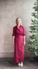 Mature woman reviewing New Earl wrap shirt Dress from TWP rendered in a vibrant red and crafted from cotton poplin in the USA with 1/2 sleeves, collar, asymetrical button top and maxi length dress
