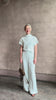 Mature woman reviewing the Dylan Pant from TWP rendered in a sea glass blue hue and crafted from a viscose and linen blend, made in the USA, this luxury mid-rise trouser offers a wide leg silhouette with hidden seam side and back pockets 
