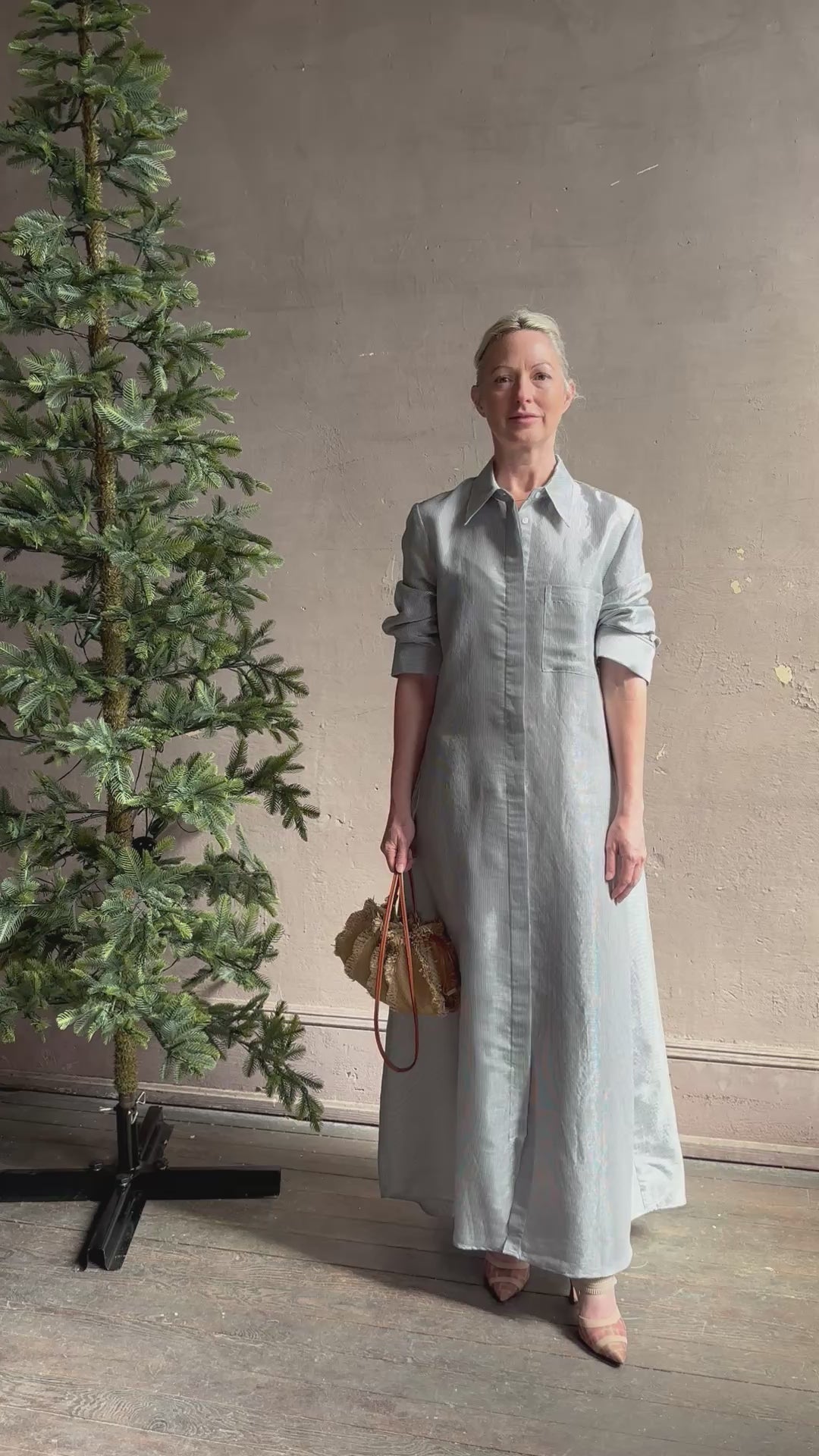 Mature woman reviewing luxury Jenny's Gown from designer TWP rendered in a lumines white and blue stripe print and crafted in USA from a viscose and lorex blend this lightweight long sleeve maxi  dress drapes beautifully with a flowing quality that moves with understated grace 