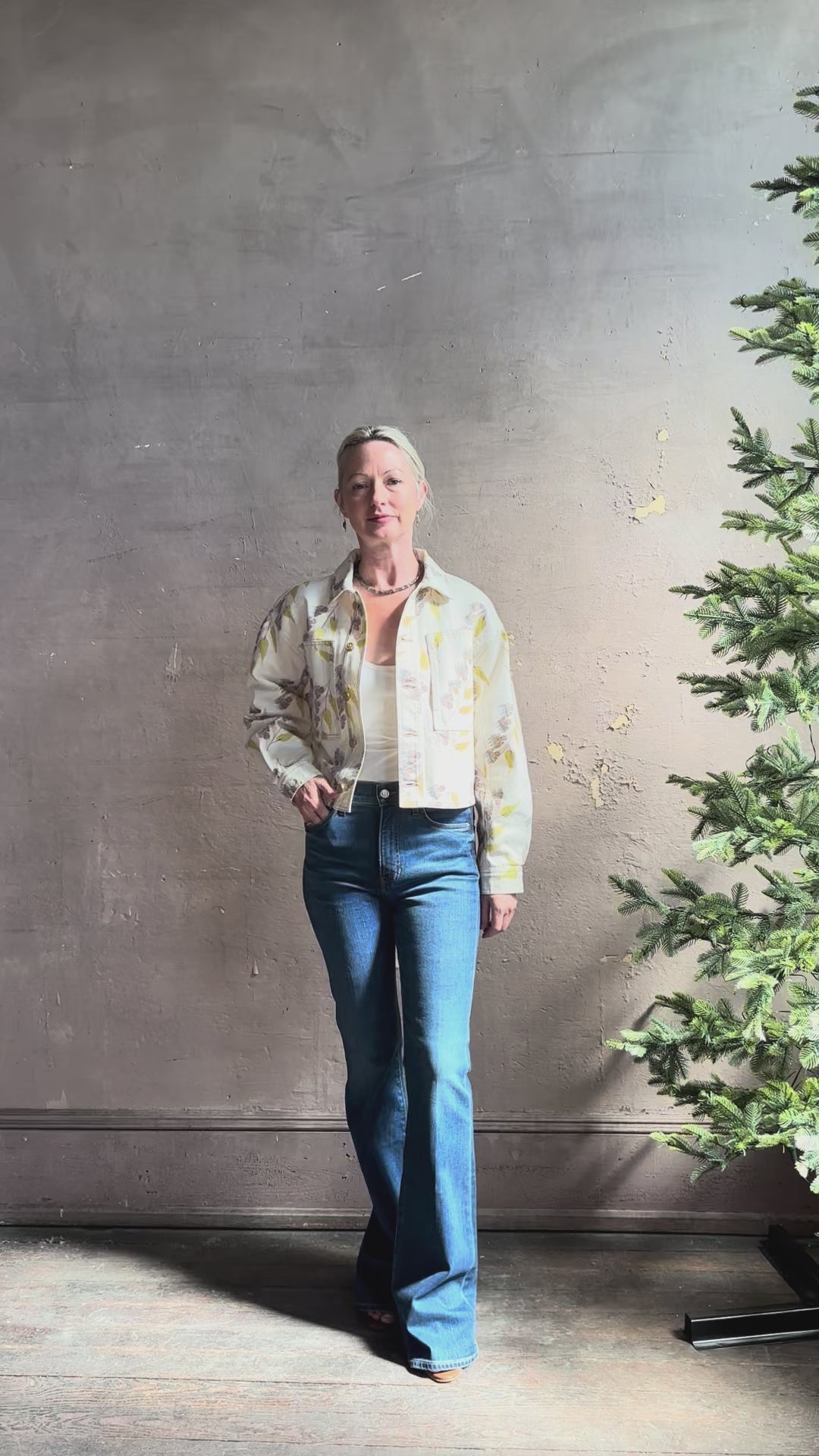 Mature woman reviewing designer ULLA JOHNSON Bobbi cotton denim Jacket in an artisan collaboration print Infinite Flower with gold buttons, front pockets and crop length cool girl vibe