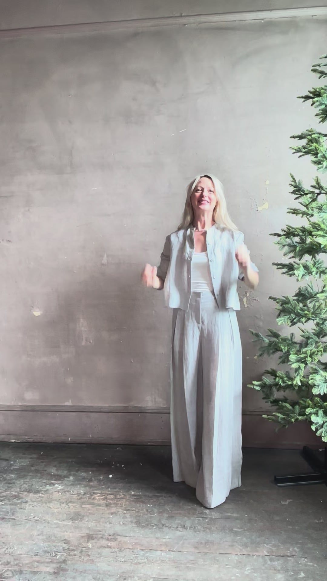 Mature woman reviewing Stand Collar Cut Off Top from TWP rendered in a versatile light heather grey and crafted from 100% hemp with round mandarin collar, button front, half sleeves and made in the USA