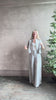 Mature woman reviewing Stand Collar Cut Off Top from TWP rendered in a versatile light heather grey and crafted from 100% hemp with round mandarin collar, button front, half sleeves and made in the USA