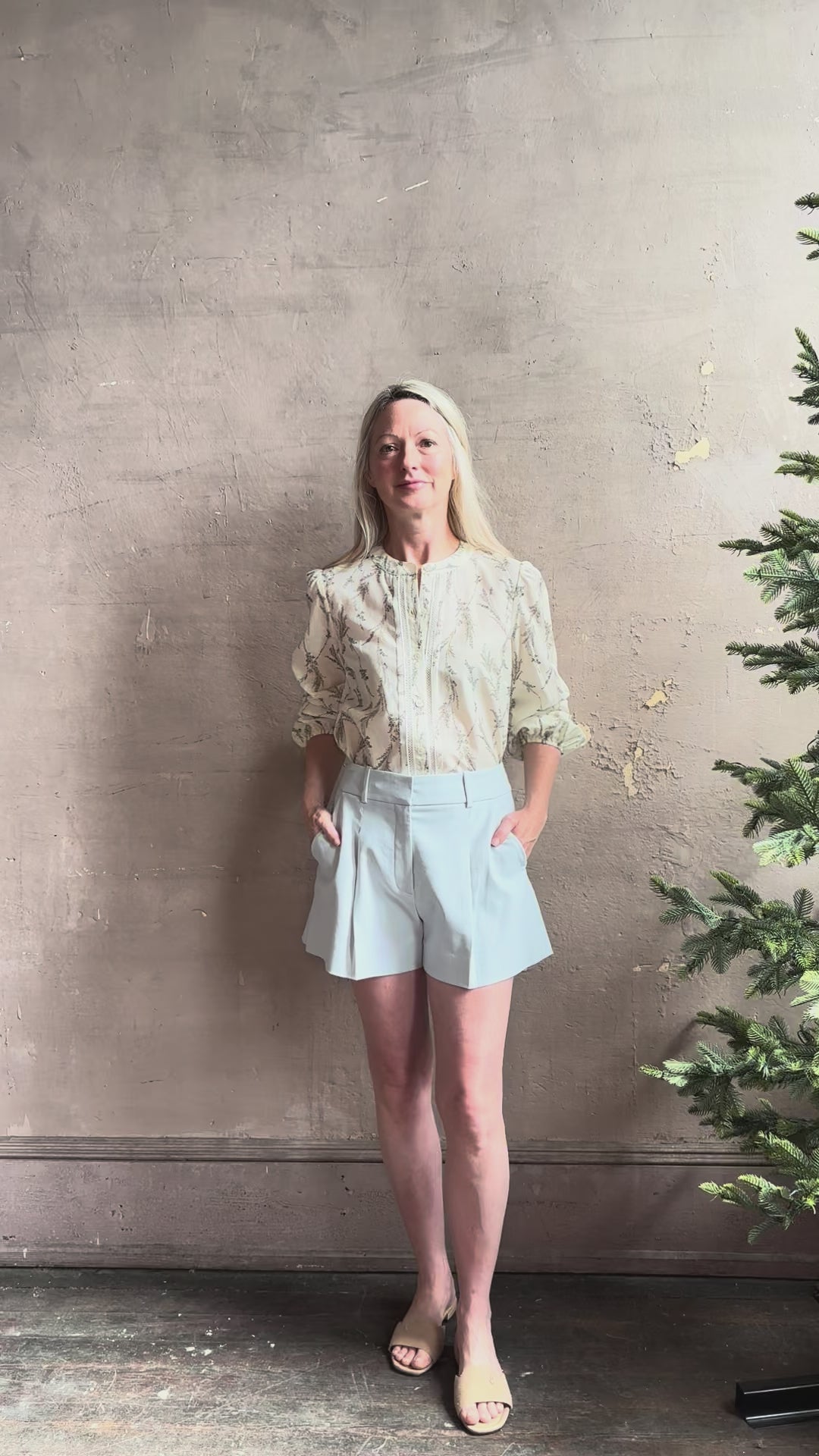 Mature woman reviewing luxurious tailored Emiko Blouse from Veronica Beard a women's designer blouse rendered in a cream  ground adorned with a delicate prairie floral print and crafted from a cotton and silk blend with long sleeves, button front and round mandarin collar.