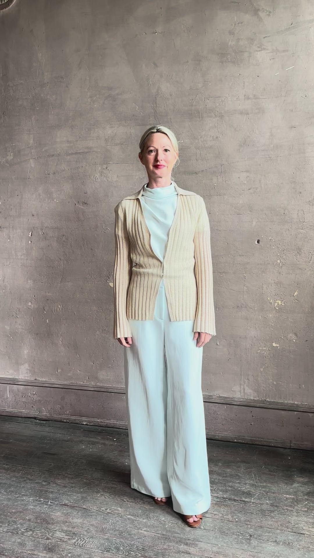 mature woman reviewing premium cashmere linen GUEST IN RESIDENCE Breezy Cardigan in Sandstone beige with long sleeves hook and eye front closure and ribbed texture