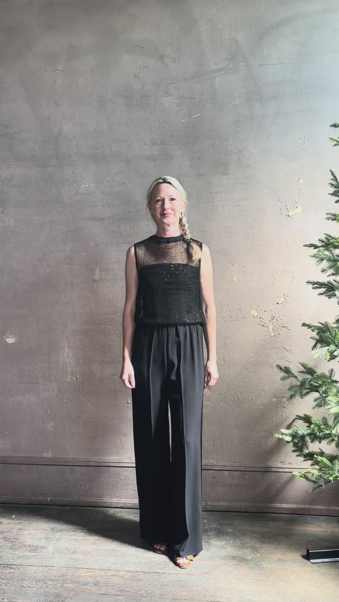 Mature model reviewing luxury Italian designer Forte Forte black wide-leg pull on pants with satin tuxedo side stripe and bottom slit