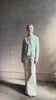 Mature woman reviewing Rib Stealth Cardigan from Guest in Residence rendered in a serene sage brush aqua green and crafted from a refined blend of 58% cashmere and 42% linen with long sleeves and a hidden hook and eye closure