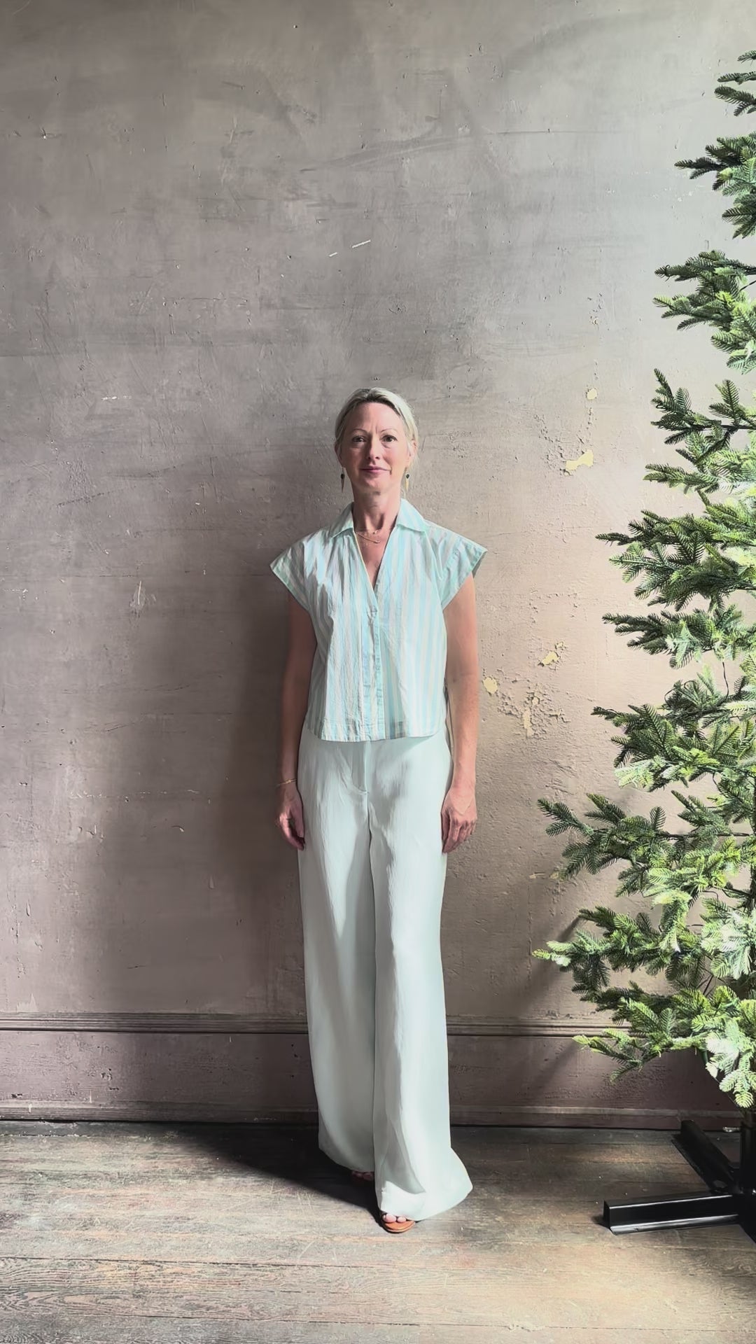 Mature woman reviewing Dorada short sleeve Shirt from Trovata rendered in a fresh aqua and cream Stripe and crafted from  cotton poplin with v-neck, collar and consealed button front