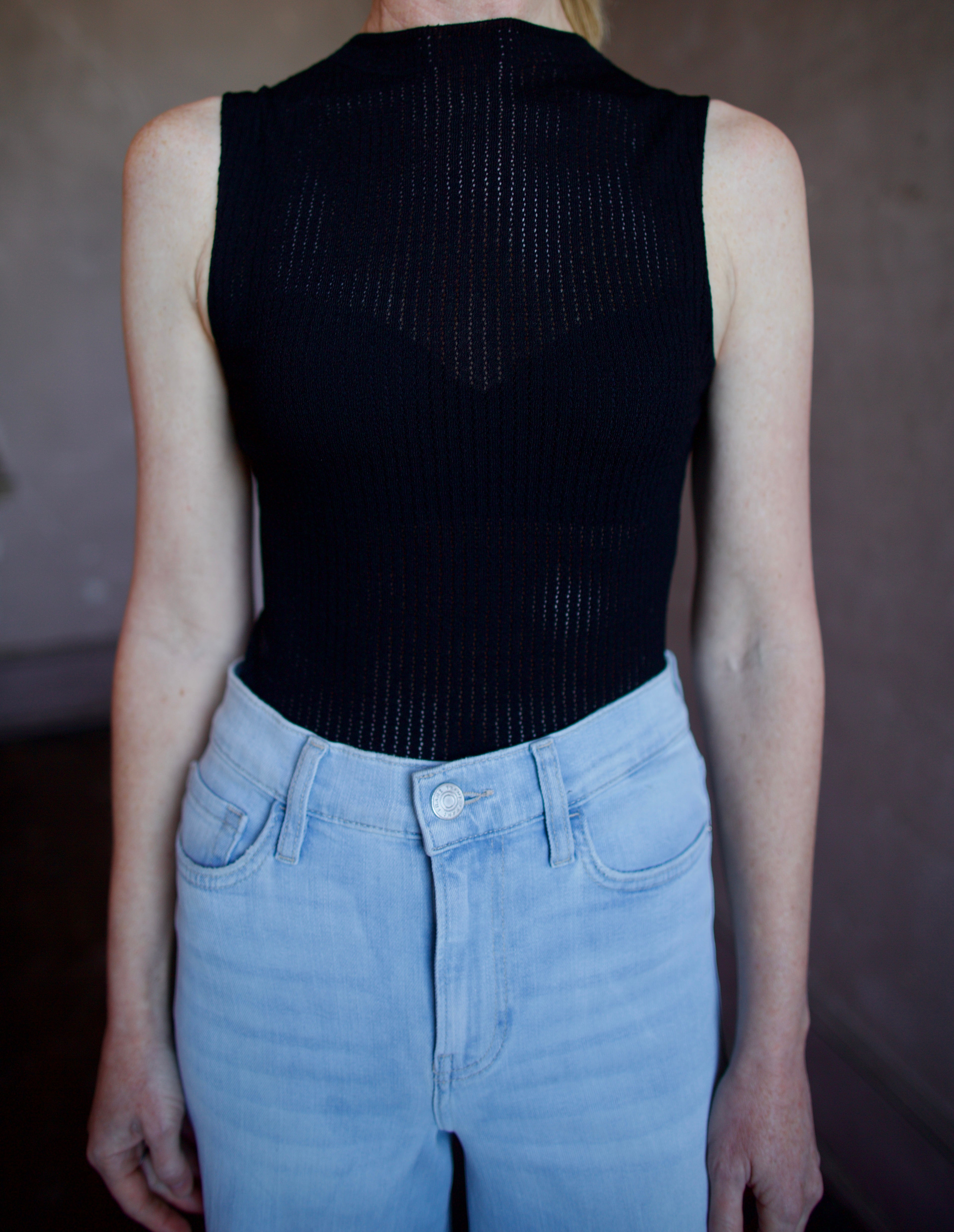 Woman wearing the Rag and Bone Molly Mock Neck black Top in semi-sheer knit construction and expertly designed minimalist silhouette