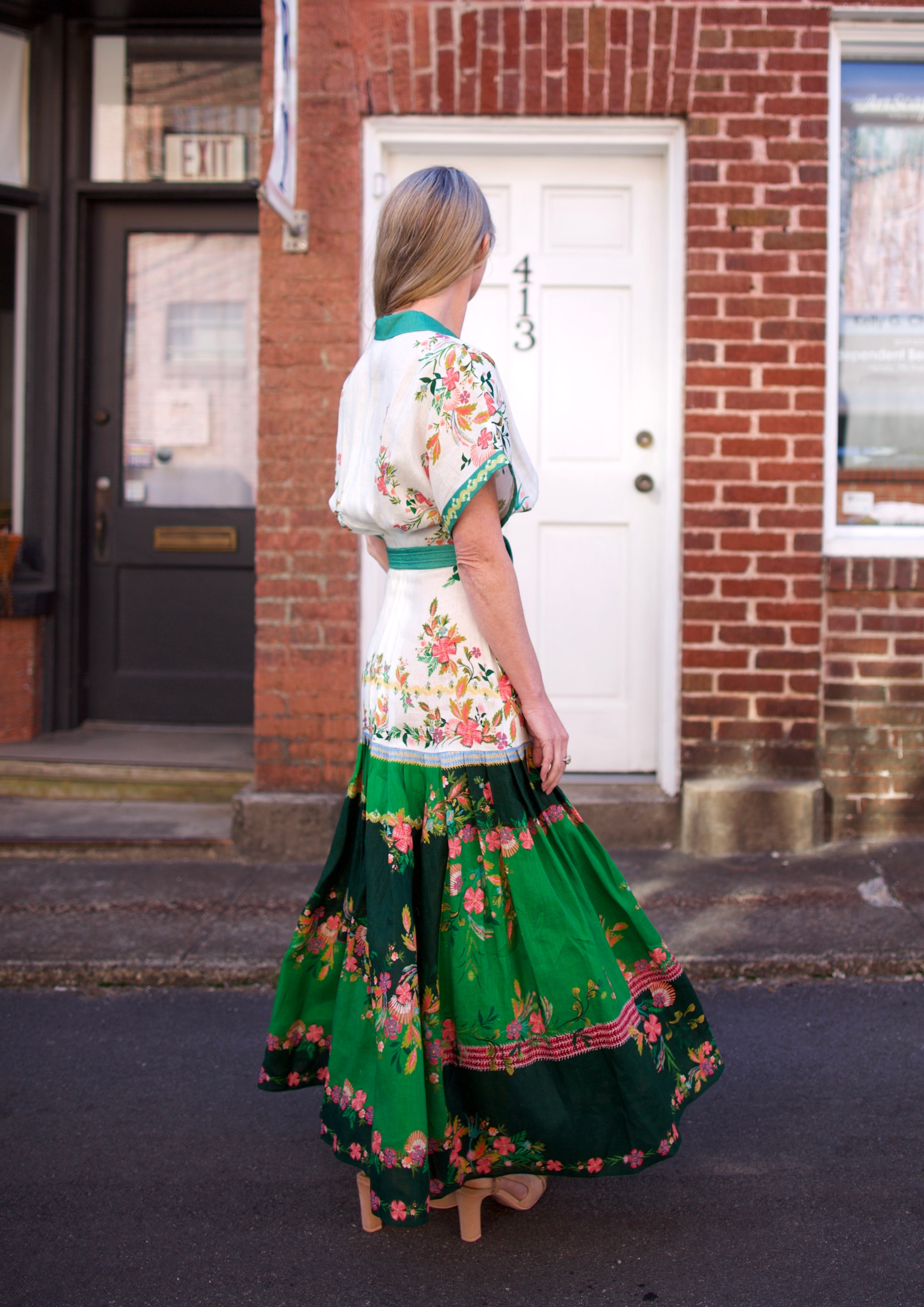 Mature woman wearing luxury women's Saloni Riya B linen dress with button front, rolled short sleeves, removable belt, and drop waist 