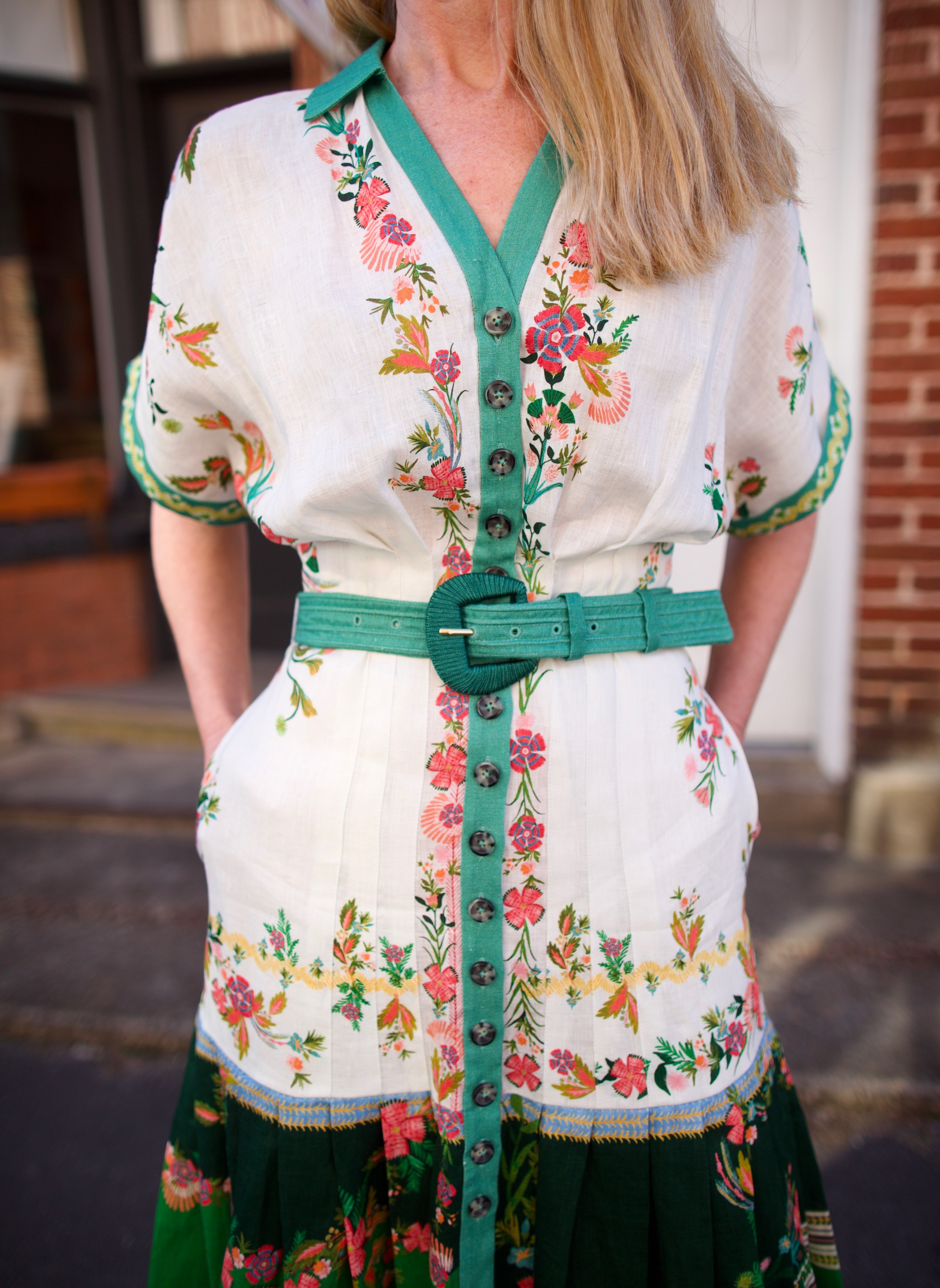 Mature woman wearing luxury women's Saloni Riya B linen dress with button front, rolled short sleeves, removable belt, and drop waist
