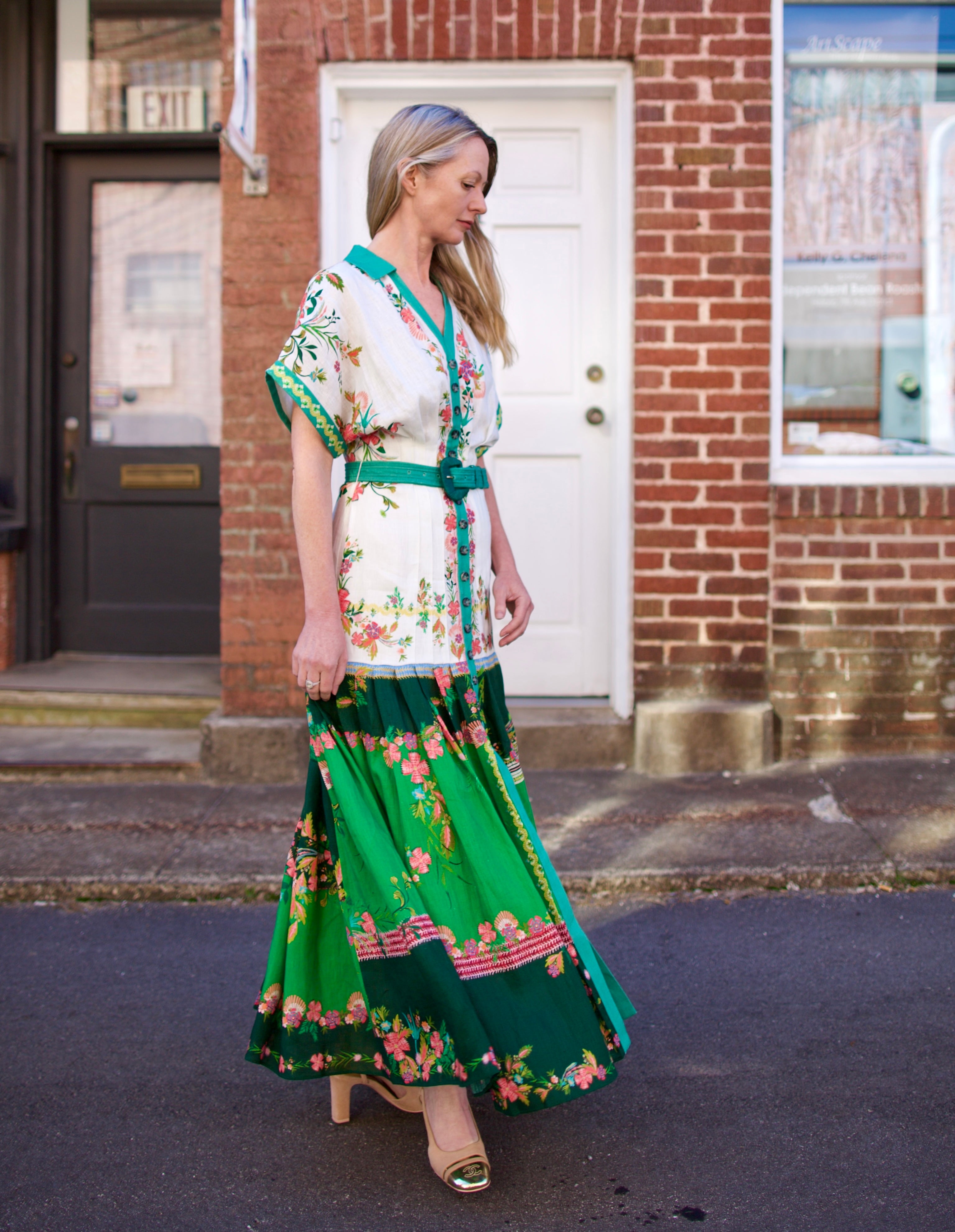 Mature woman wearing luxury women's Saloni Riya B linen dress with button front, rolled short sleeves, removable belt, and drop waist