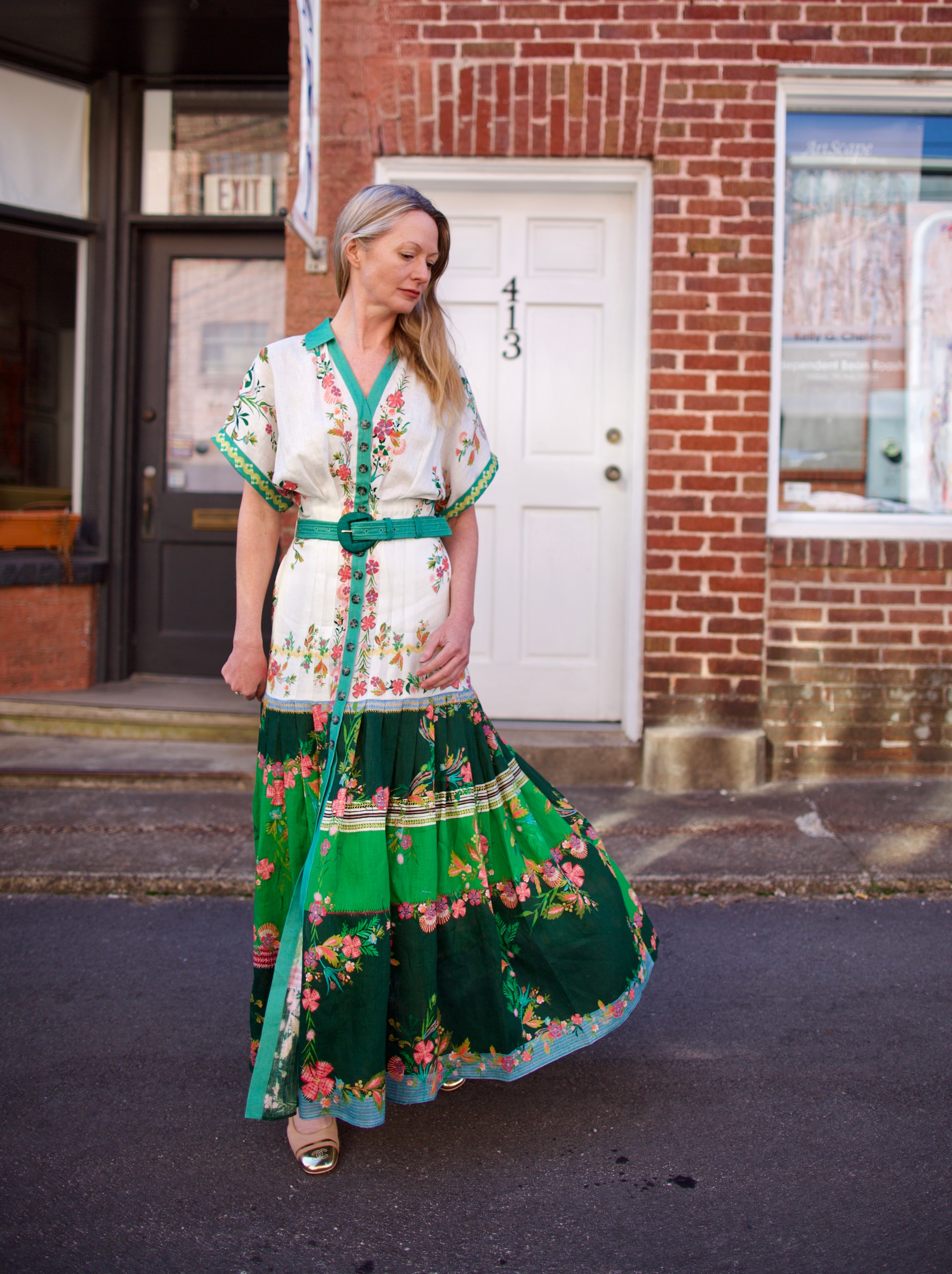 Mature woman wearing luxury women's Saloni Riya B linen dress with button front, rolled short sleeves, removable belt, and drop waist
