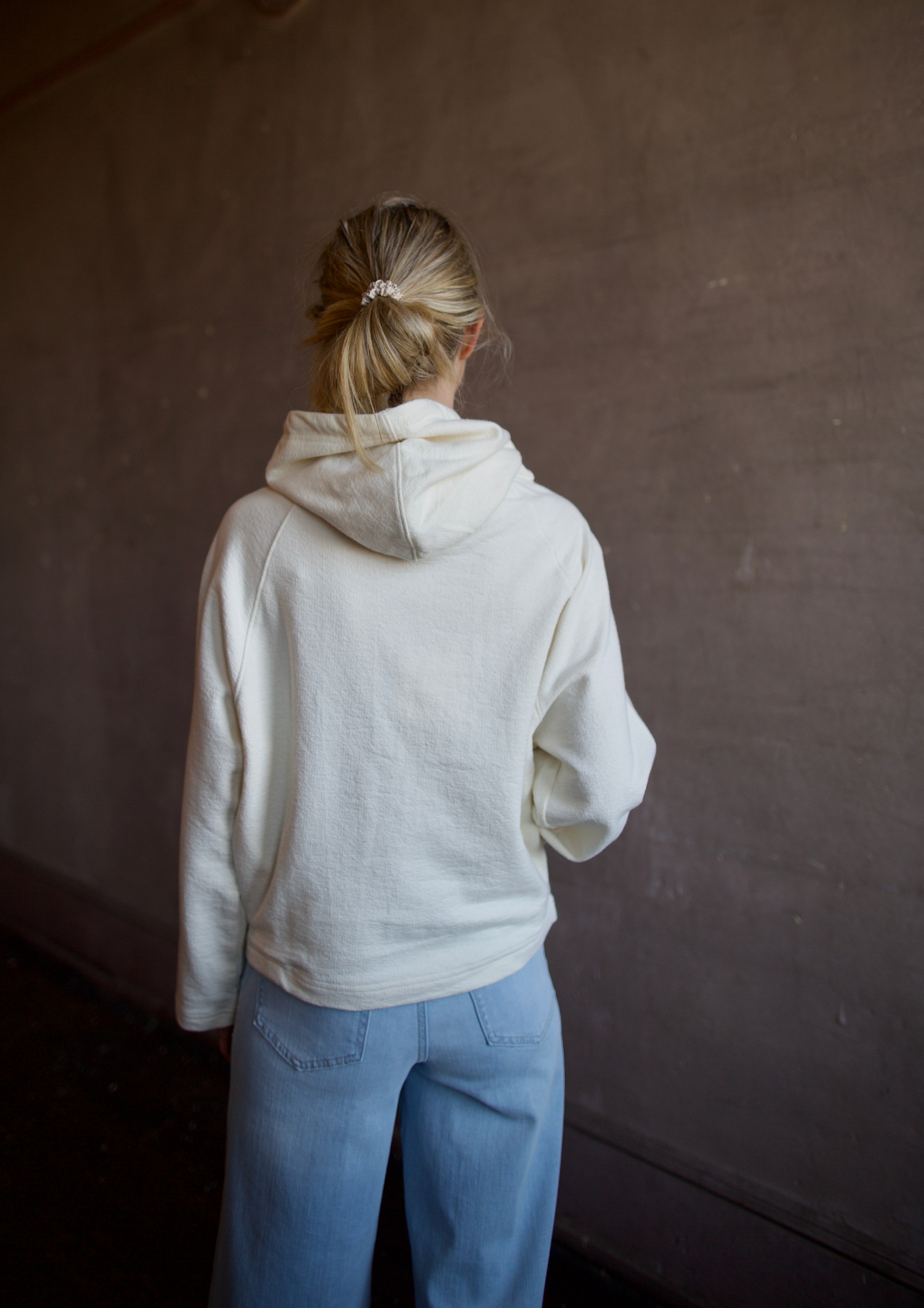 Mature woman wearing luxury TWP Ali's ivory Hoodie featuring raglan sleeves and kangaroo pocket with boxy fit, delivering elevated comfort