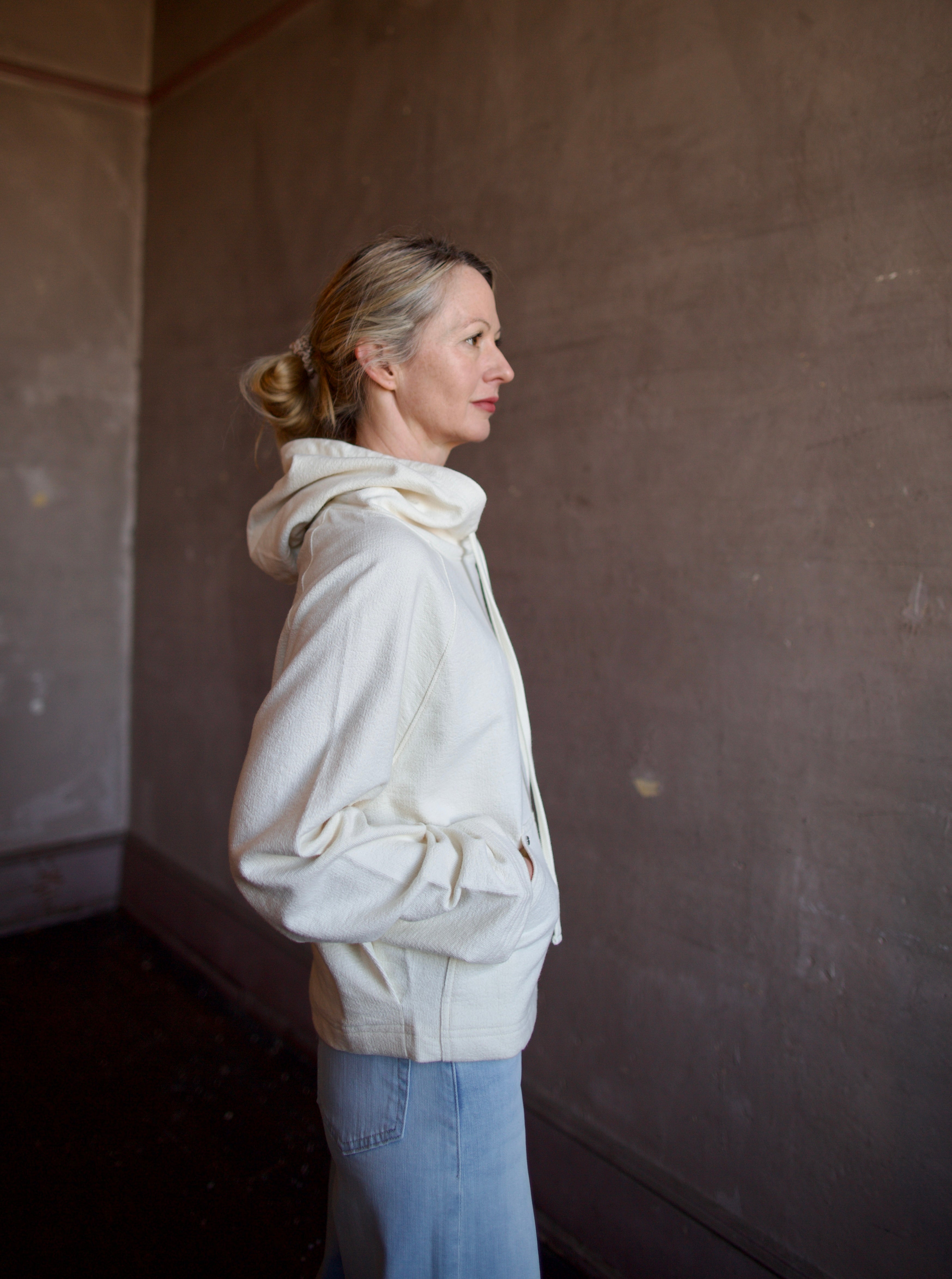 Mature woman wearing luxury TWP Ali's ivory Hoodie featuring raglan sleeves and kangaroo pocket with boxy fit, delivering elevated comfort