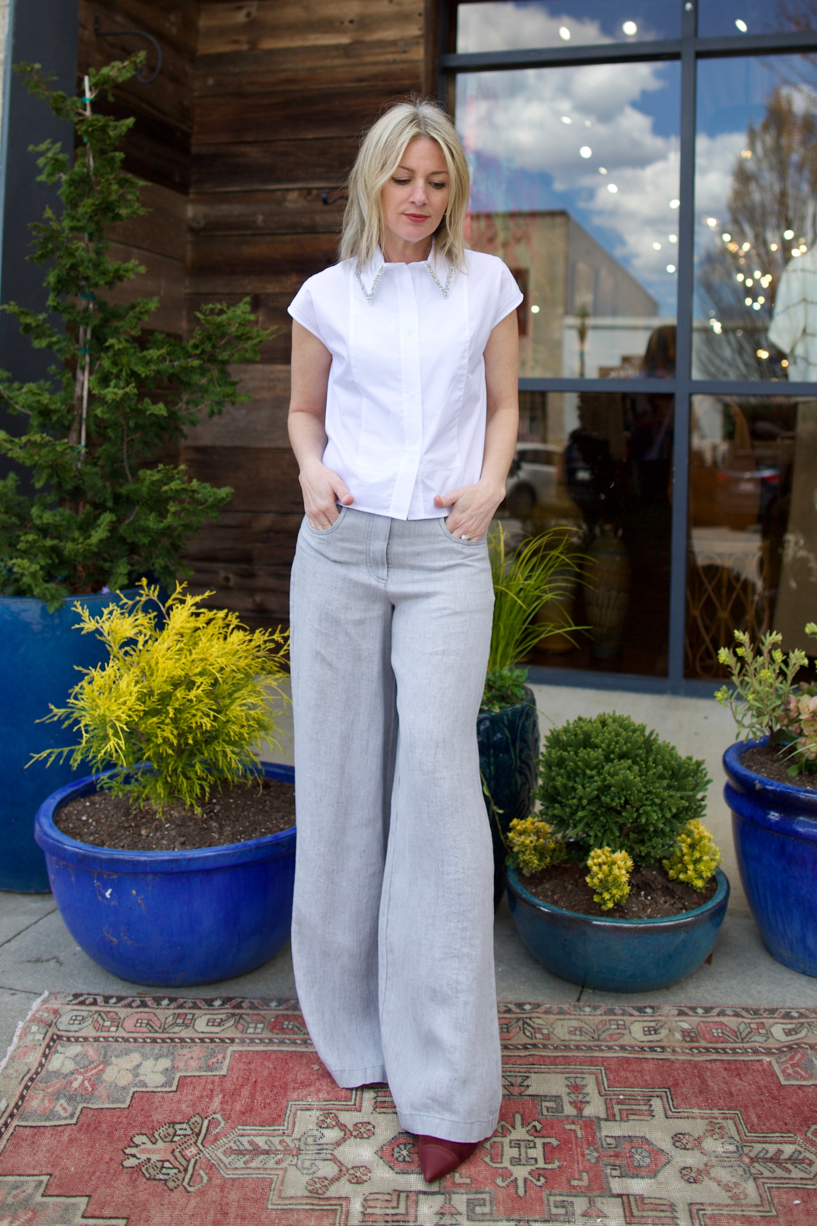 Mature model wearing luxury brand TWP white cap sleeve top with detachable crystal beaded collar in premium cotton Jeans