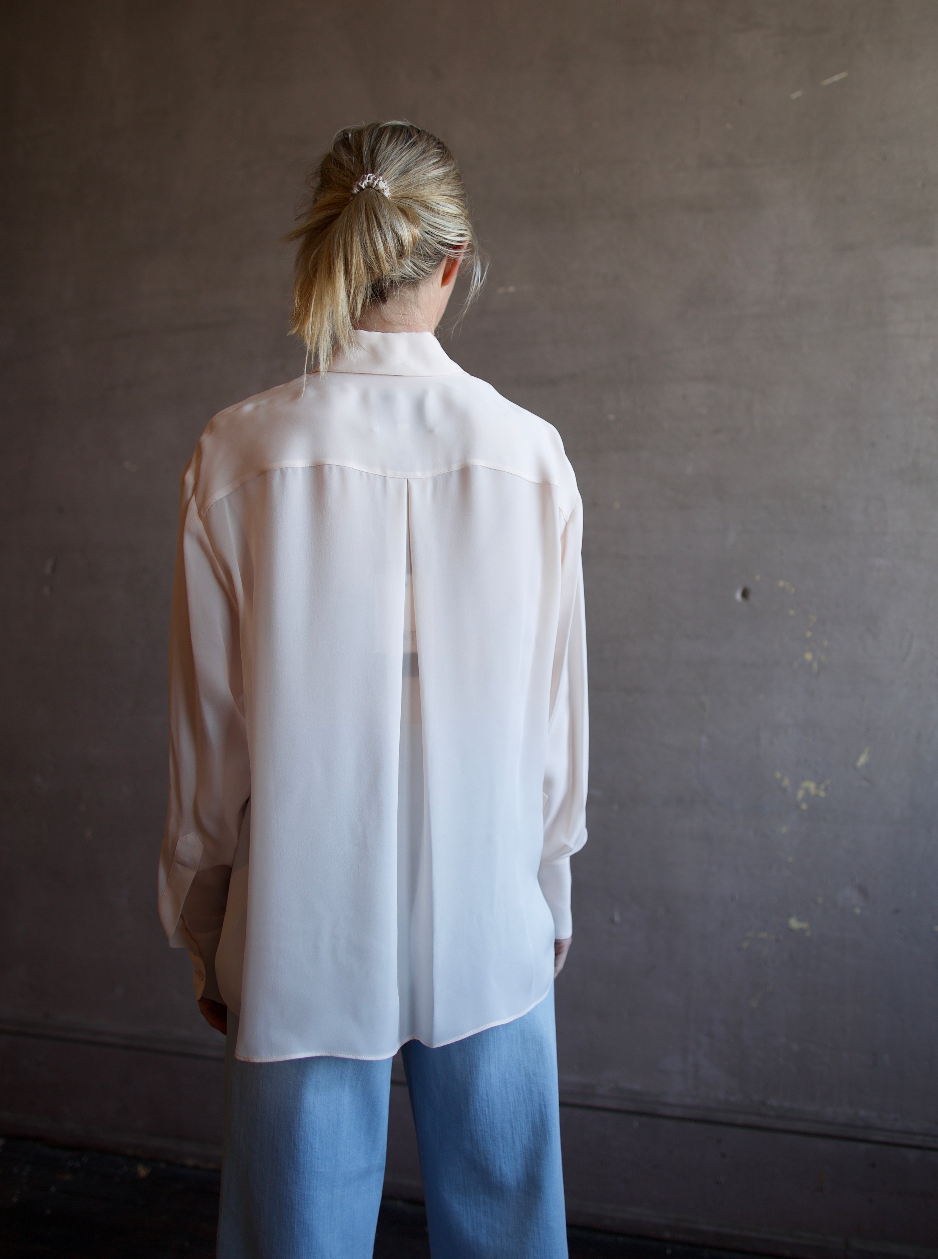 Mature woman wearing luxury women's pink sheer silk Joey blouse by TWP with front pocket, delivering sophisticated elegance