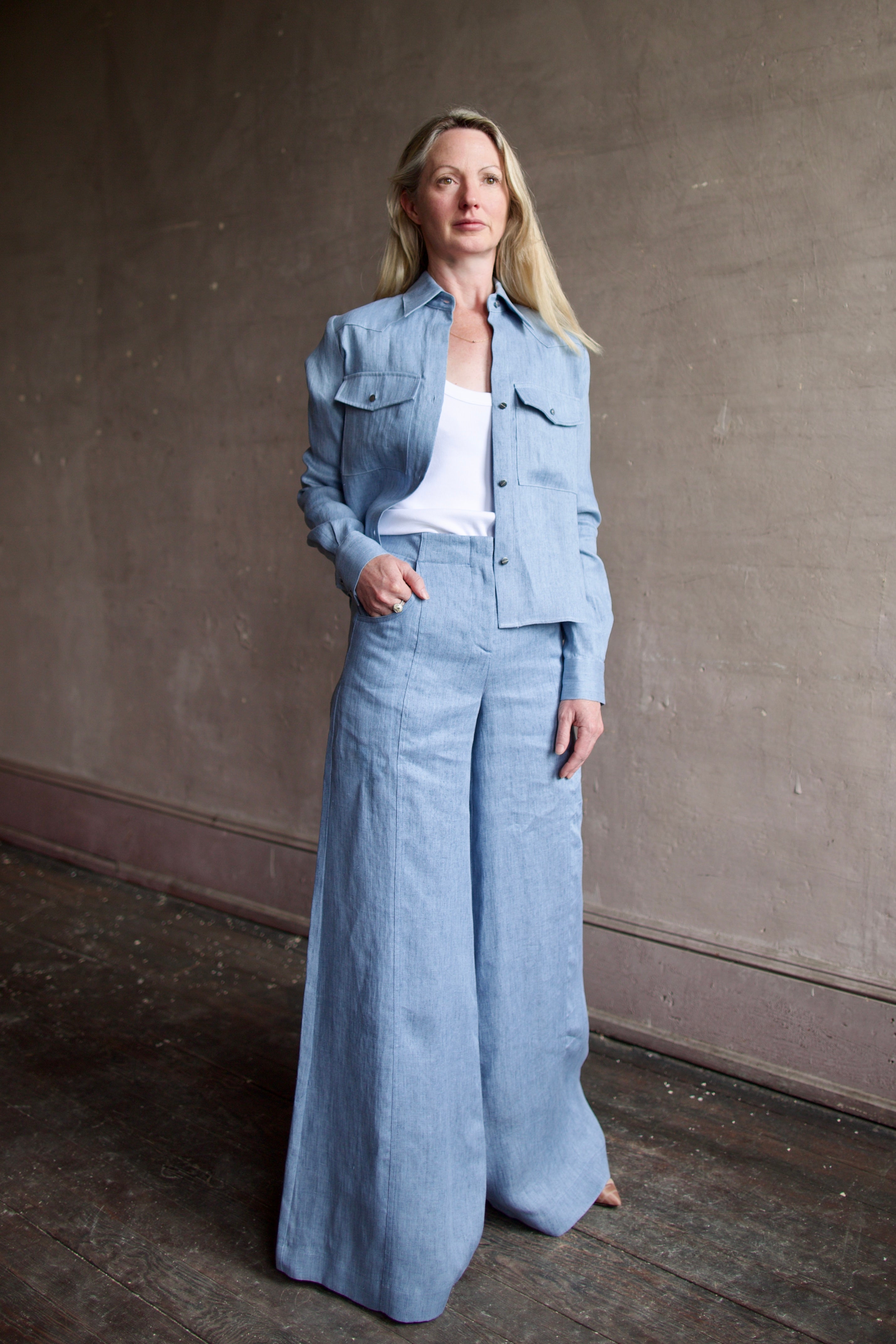 Image of a woman wearing the TWP New Carter Button Up Top and Demie High Rise Flare Pants