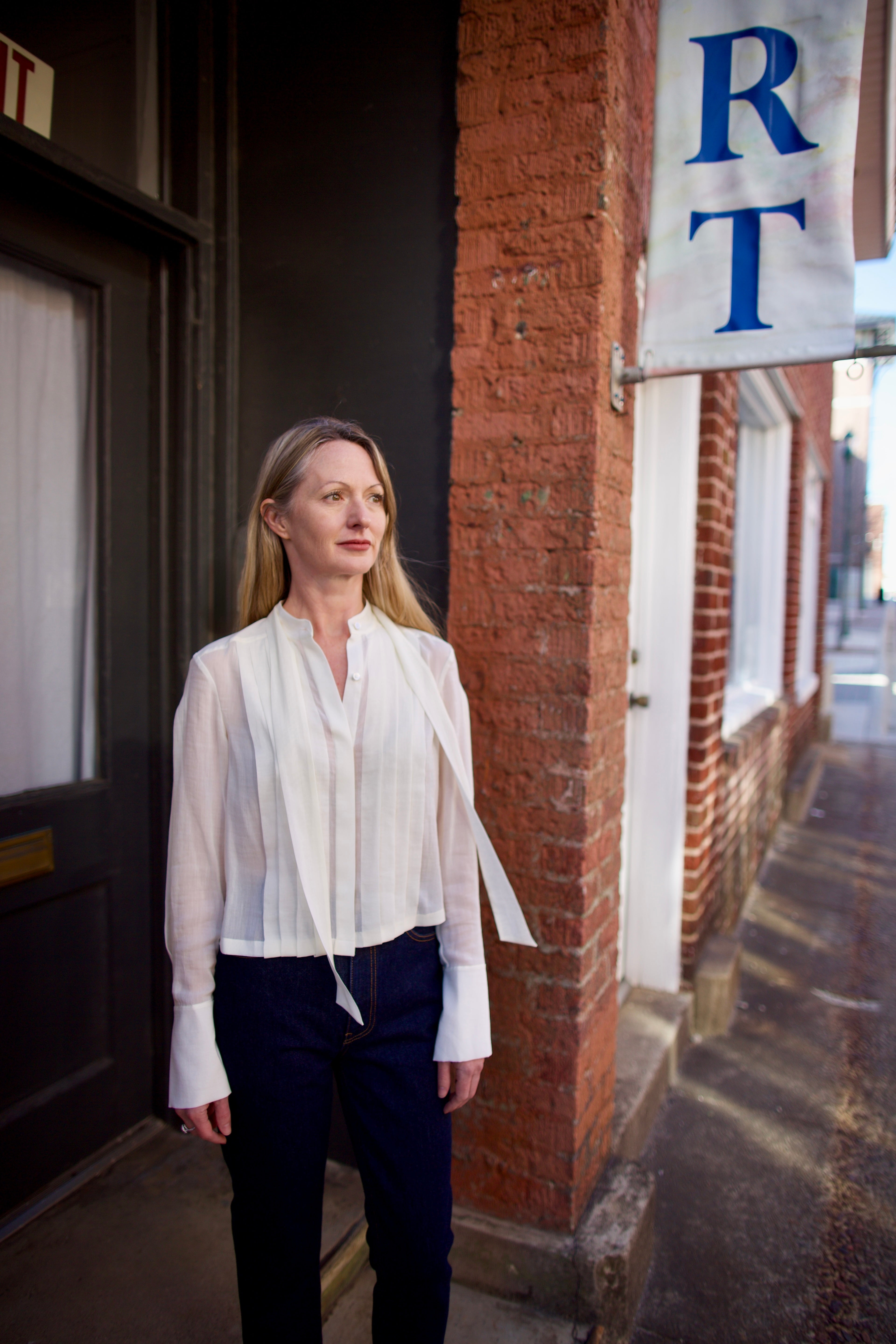 Mature woman wearing elegant luxury women's ivory cotton-silk Patti blouse by TWP with front pleats and buttons  in a slightly cropped fit