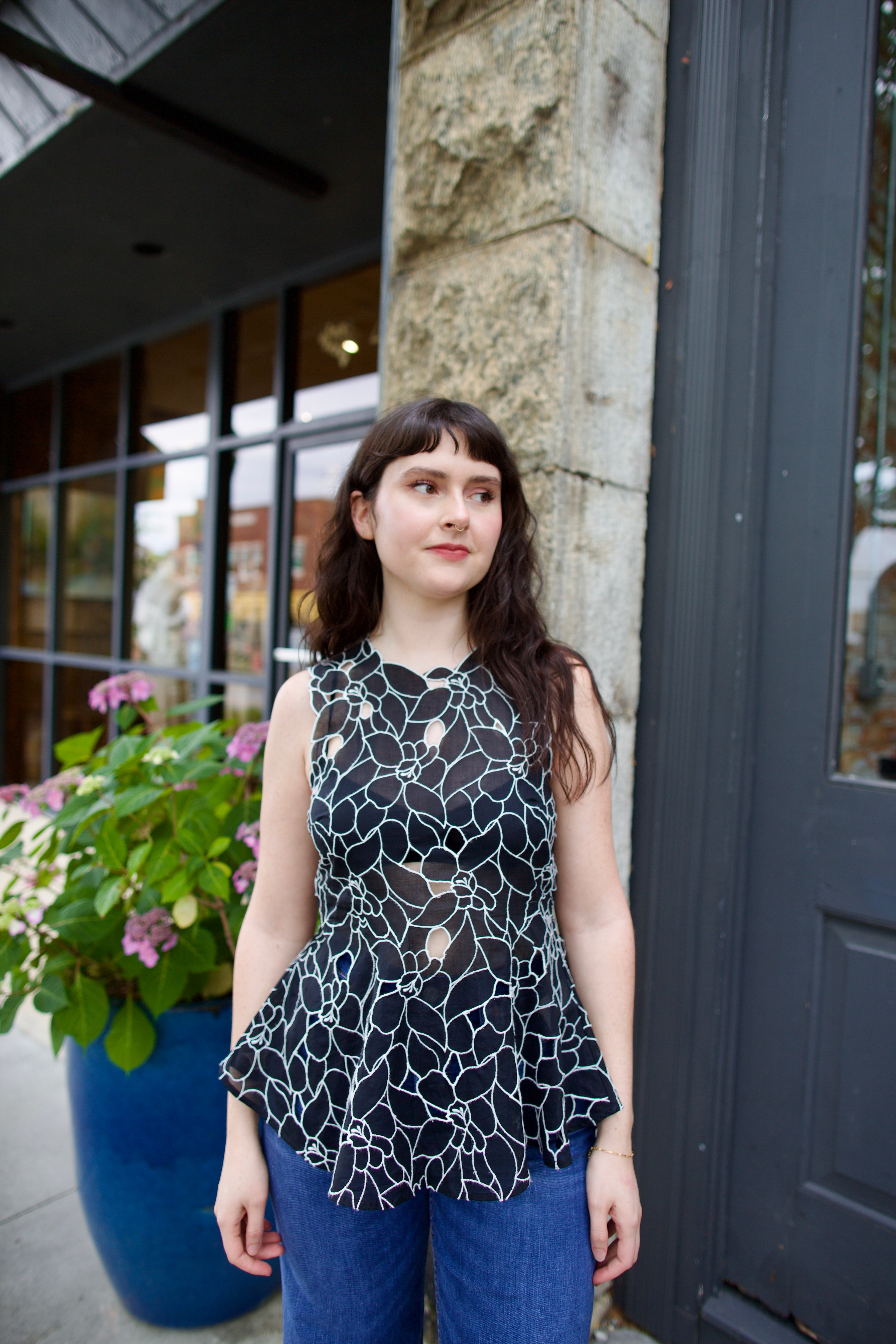 Model wearing the Ulla Johnson Ali Sleeveless black cotton peplum top with contrast white embroidery for ultimate feminine sophistication