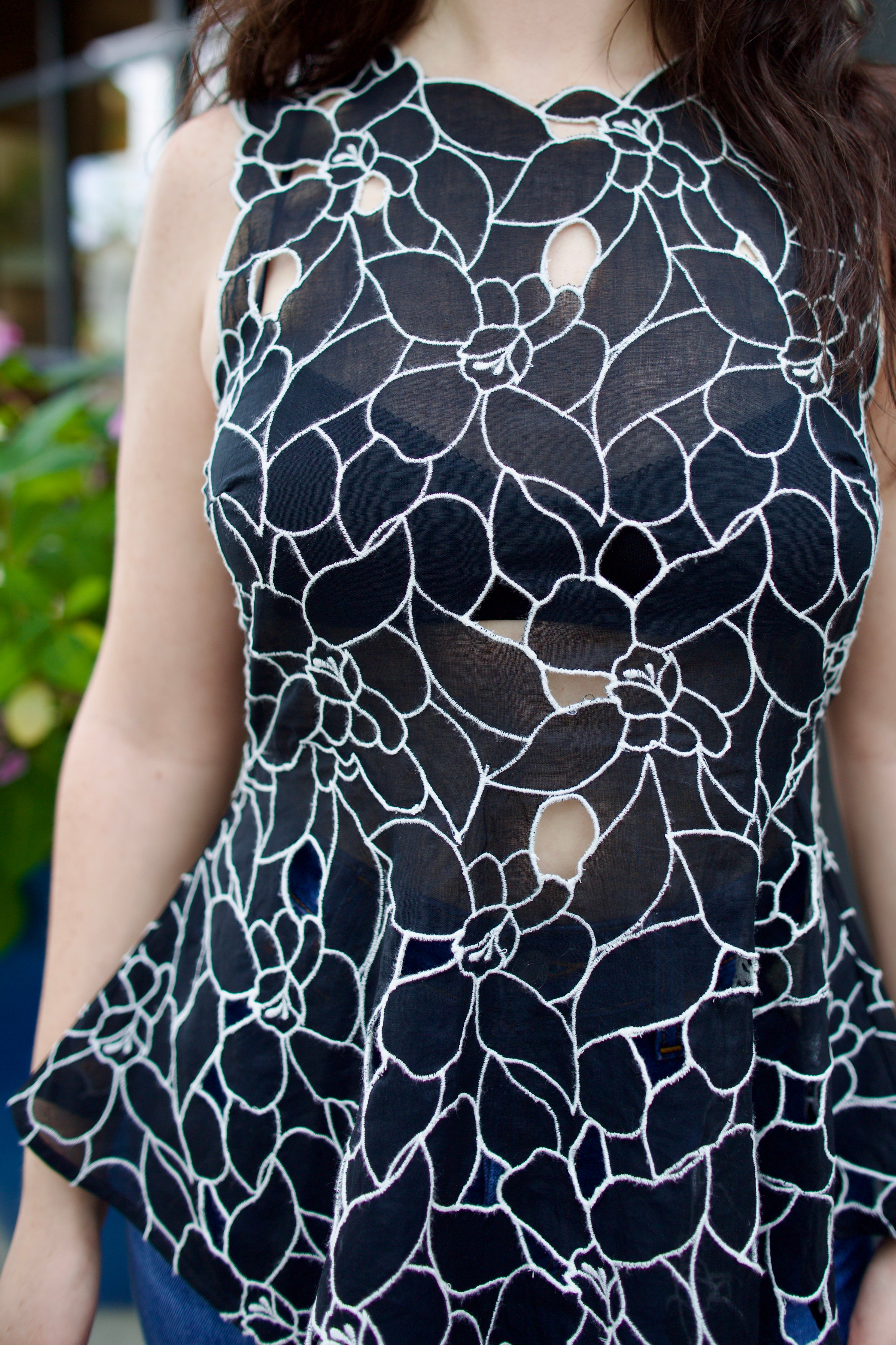 Model wearing the Ulla Johnson Ali Sleeveless black cotton peplum top with contrast white embroidery for ultimate feminine sophistication