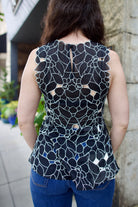 woman wearing the Ulla Johnson Ali Sleeveless black cotton peplum top with contrast white embroidery for ultimate feminine sophistication