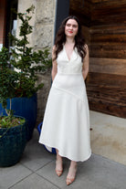 Woman wearing Ulla Johnson Florence Dress in textured off-white cotton blend with a v-neckline asymmetrical hem and v-neckline