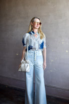 Mature woman wearing Ulla Johnson Gwynne Cielo Jeans in recycled cotton gold button fly light wash front pockets