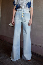 Mature woman wearing Ulla Johnson Gwynne Cielo Jeans in recycled cotton gold button fly light wash front pockets