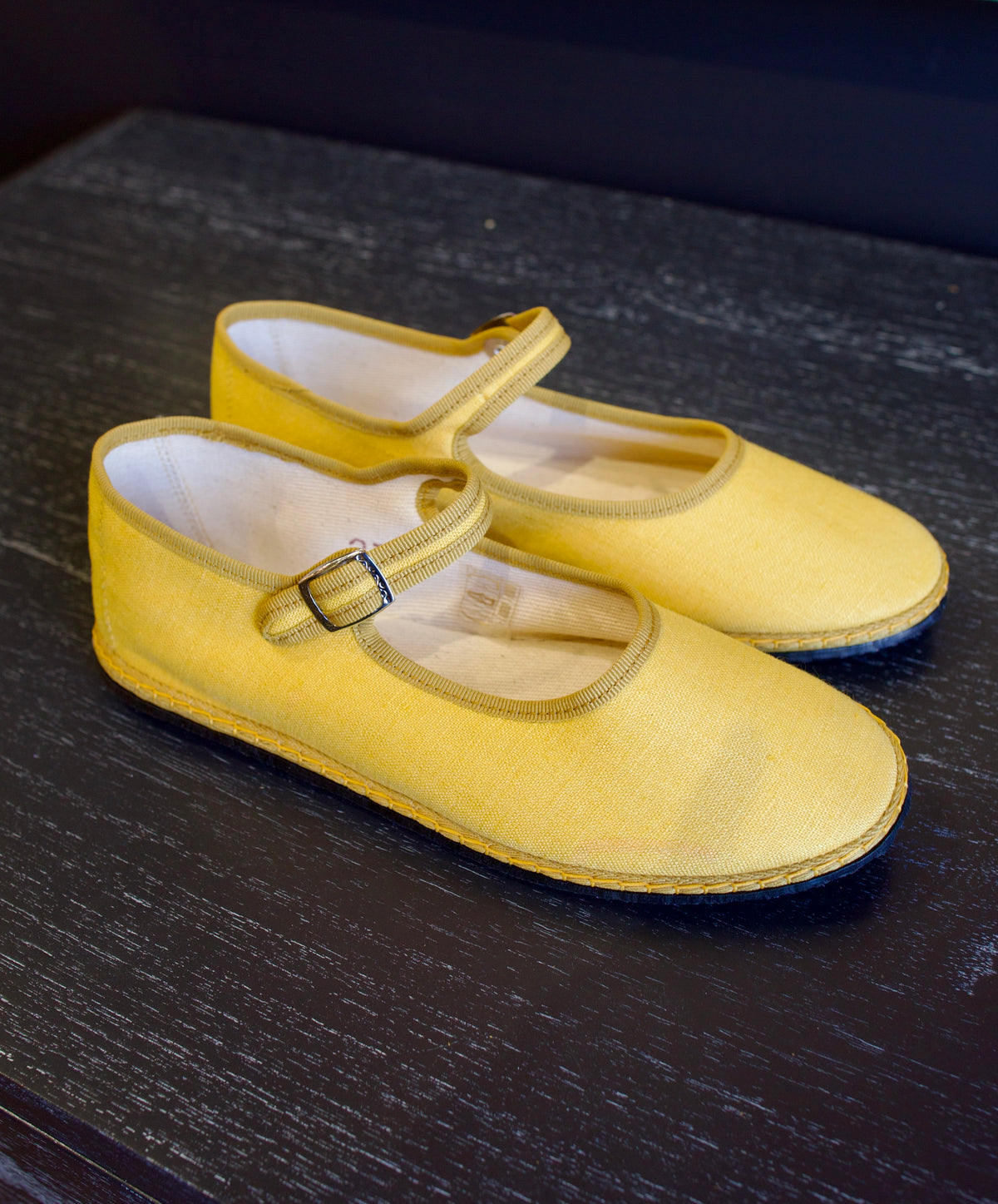 A pair of yellow Vibi Venezia slippers with yellow grosgrain ribbon trim in premium linen construction and traditional Mary Jane design